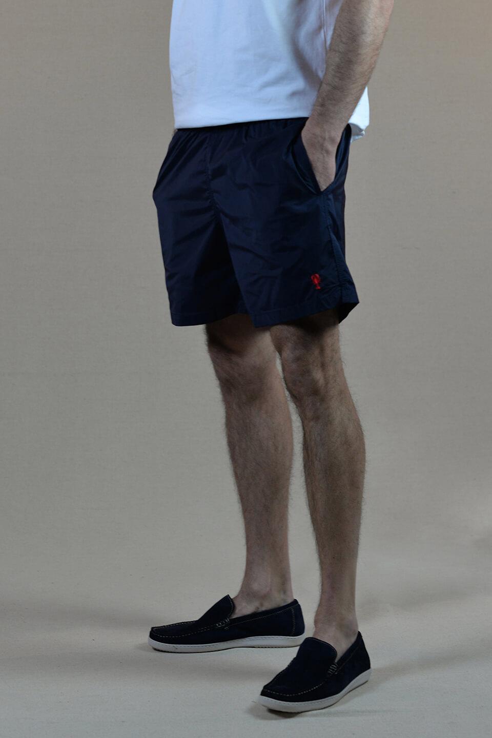 Homme de profil portant un short de bain bleu marine uni brode d'un petit homard.