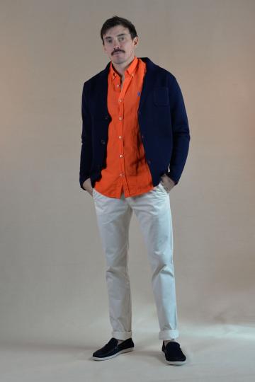  Homme de face présentant un style élégant avec un cardigan bleu marine, chemise orange, pantalon chino blanc et mocassins noirs.