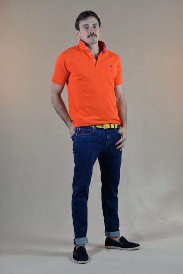 Homme de face portant un jeans bleu brode d'un petit homard rouge et un polo col mao orange.