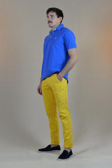 Homme de profil portant un polo bleu roi et un jaune.