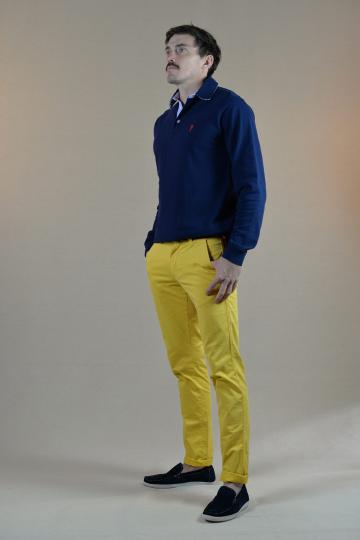Homme de profil portant un polo à manches longues bleu marine et un un chino jaune.