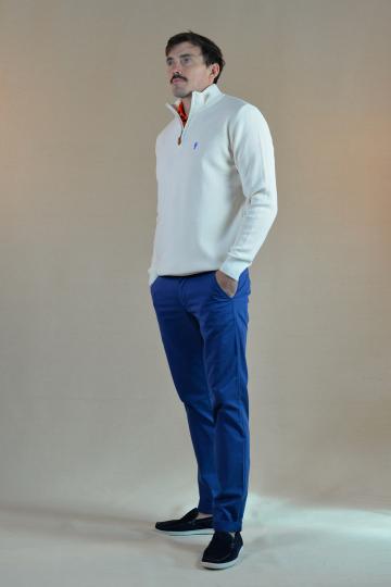 Homme de profil portant un pull marin col montant blanc brode d'un petit homard bleu et un chino bleu.