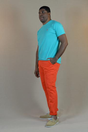 Homme de profil portant un tshirt turquoise avec petit homard orange et un chino orange.