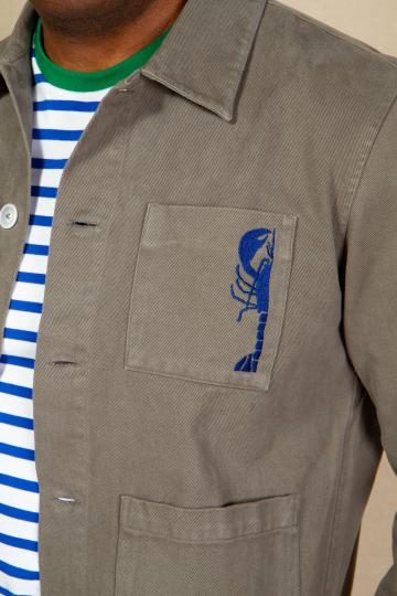 Zoom sur homme de profil portant une veste de marin kaki et une marinière bleue.